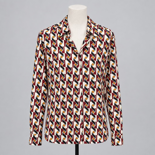 A long-sleeve button-up shirt with a bold geometric pattern in red, yellow, blue, and black on a white base, displayed on a mannequin in a clothing boutique.